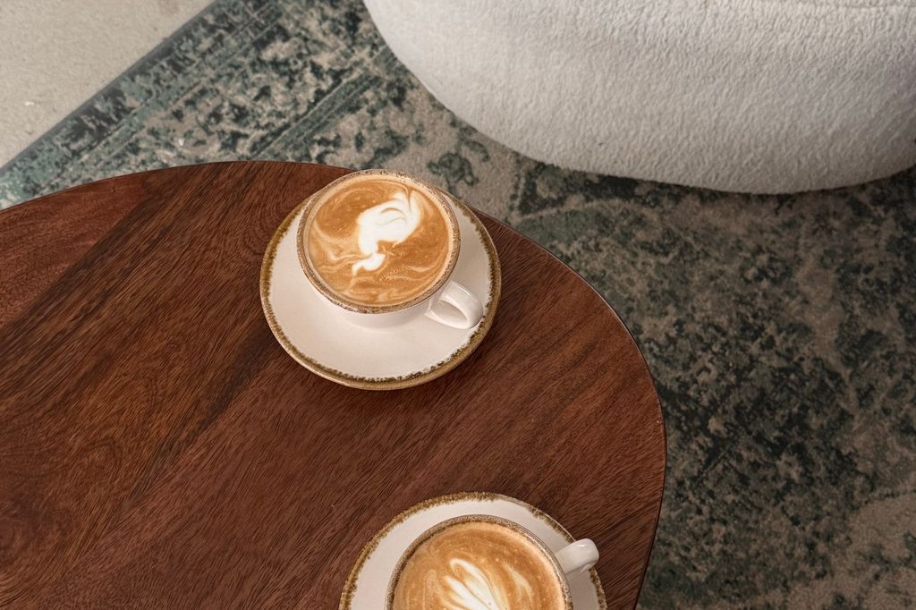 Dve cappuccina s latte art na drevenom stole v kaviarni