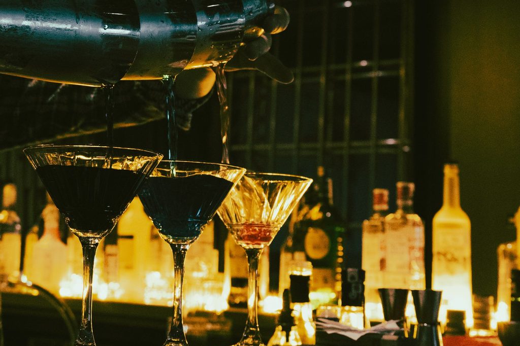 Barman nalieva koktaily do pohárov v tmavom bare
