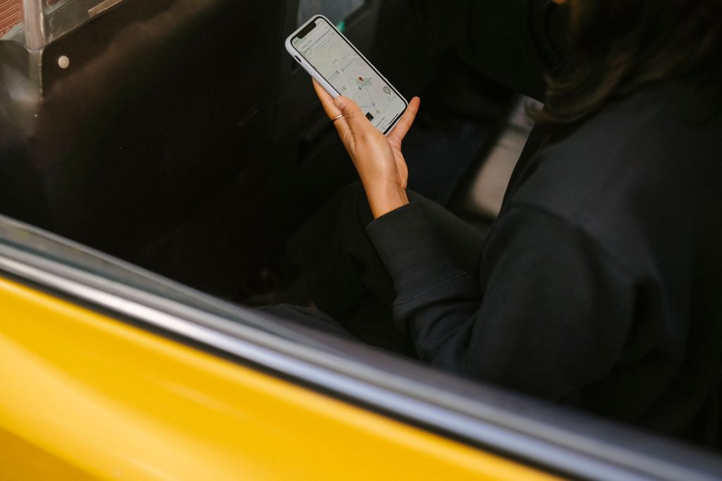 Cestujúci na zadnom sedadle taxíka sleduje mapu v mobilnej aplikácii